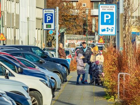 cars parked along a street with people on the sidewalk