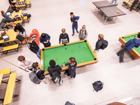 Viewed from above, students play pool on a green table during recess at Ölduselsskóli.