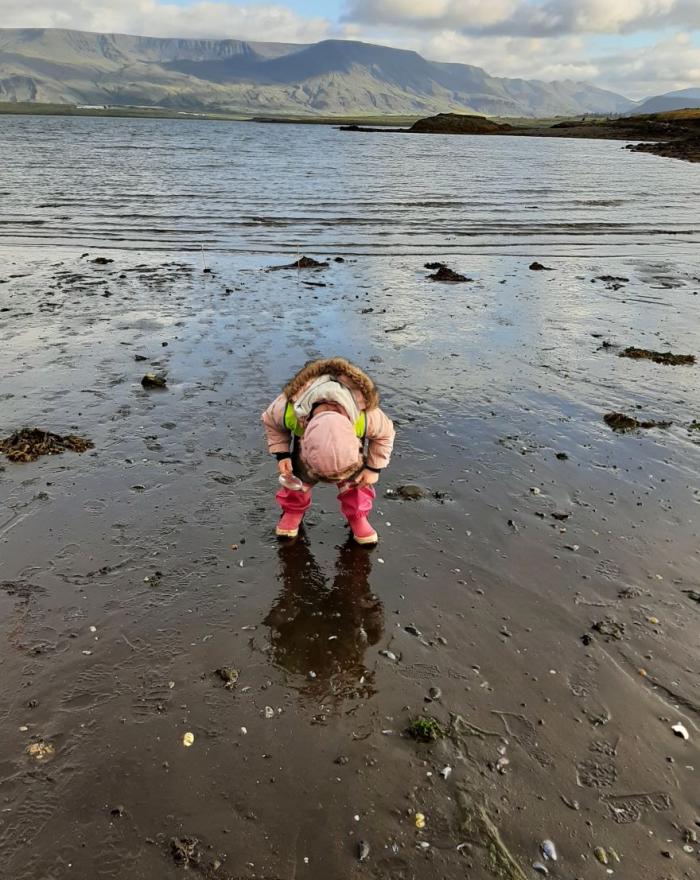 Child in pink overalls at the shoreline