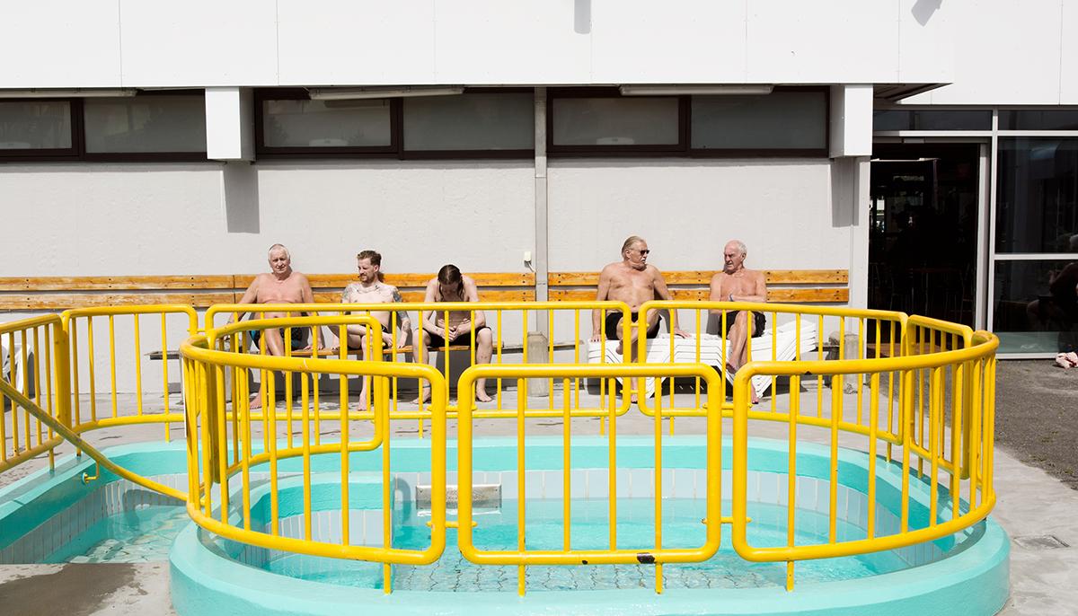 Visitors sunbathing on benches at Breiðholtslaug