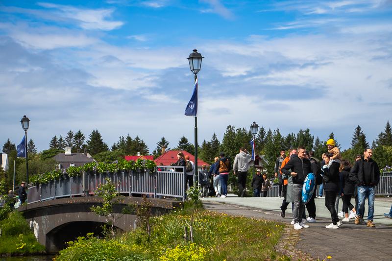 People walking across the bridge to Hljómskálagarður