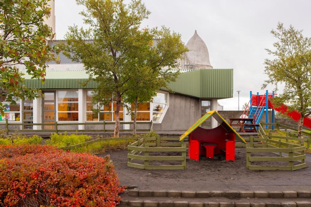 Outdoor area at Grænaborg preschool with small house, tree and slide