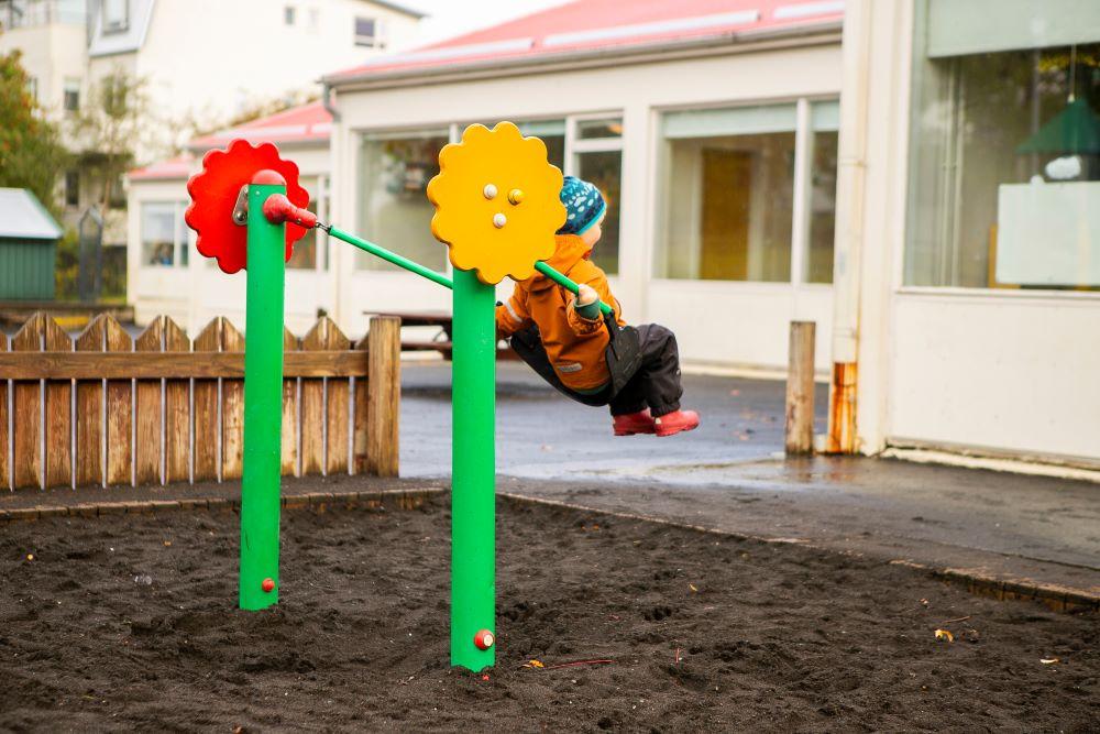 Child swinging in the outdoor area at Bjartahlíð preschool
