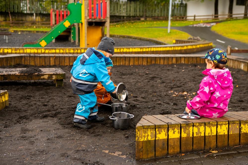 Children playing in a sandbox in the outdoor area at Bjartahlíð preschool