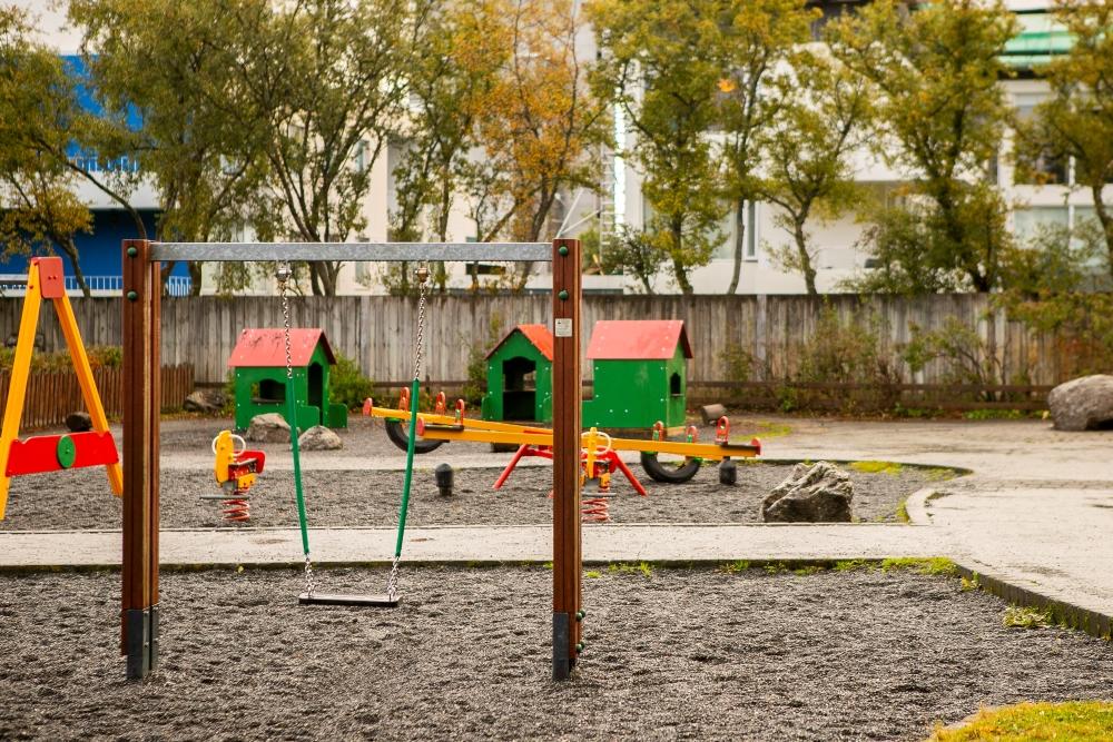 Swings, road salt, small houses along with other playground equipment in the outdoor area at Bjartahlíð preschool