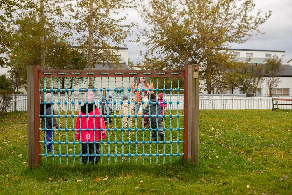 Children playing soccer viewed through a soccer goal in the outdoor area of Gullborg Preschool