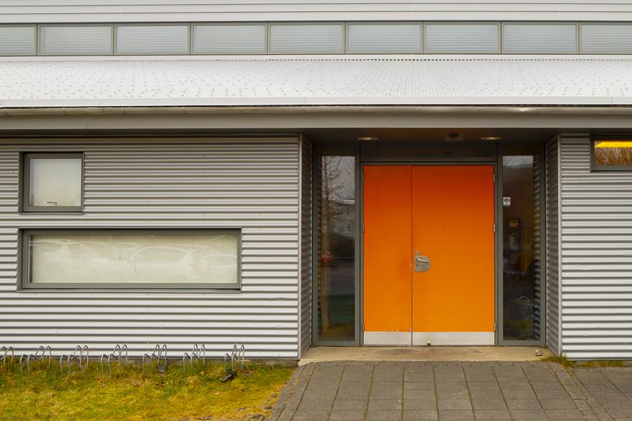White house with orange door that houses Nes preschool at Hamravík