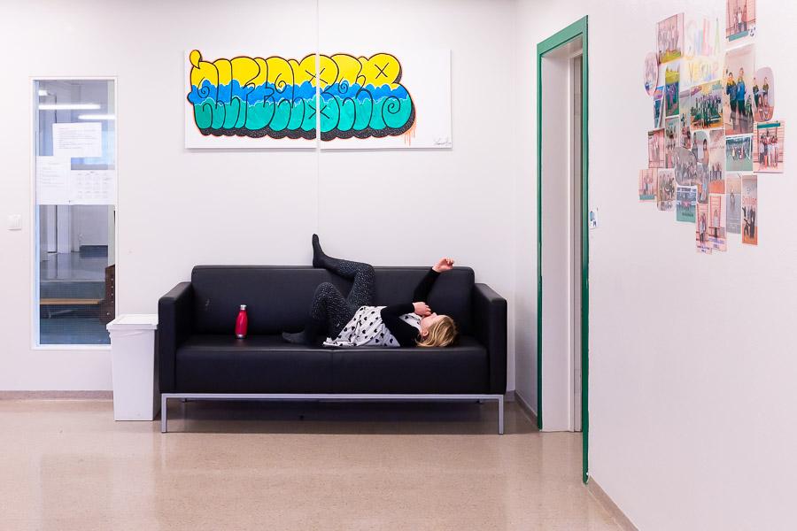 Child lying on a black sofa. Picture on the wall with decorative letters.