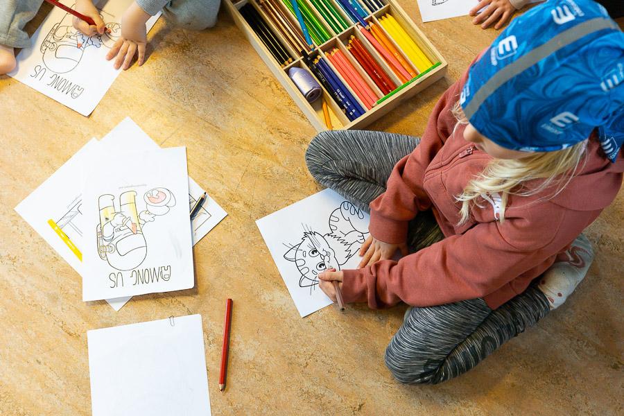 Children sit on the floor drawing. 