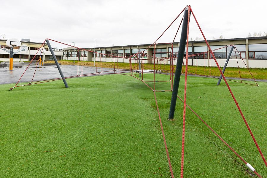 Large jungle gym with red rope standing on artificial grass. 