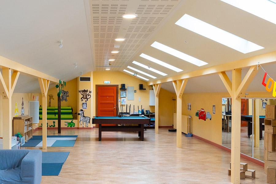 A hall with a pool table, rugs and pictures of animals on the walls.