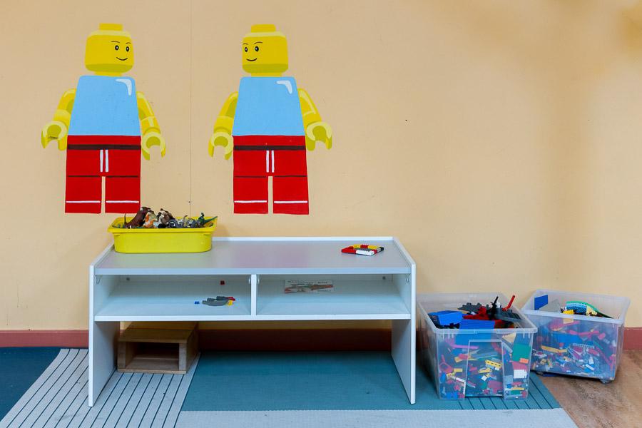 A table with Lego blocks along with pictures of Lego figures on the wall