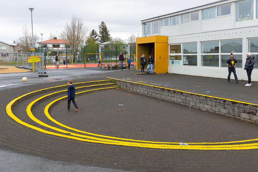 Outdoor area at Hlíðaskóli and Eldflaugin after-school program. Yellow semicircle painted on stairs with a child in the hallway.