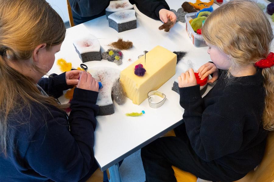 Children sit at a table doing crafts. 