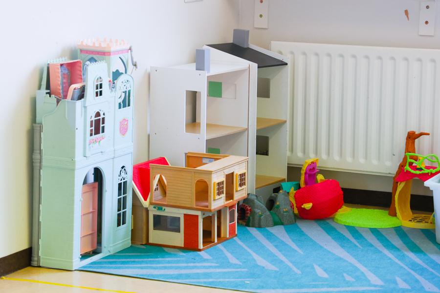 A dollhouse on a blue rug.