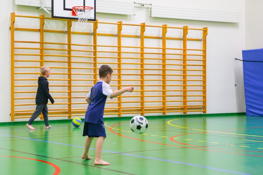 Children playing soccer on an indoor field.