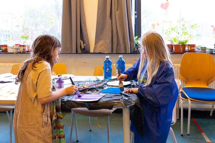 Children painting pictures at a table. 
