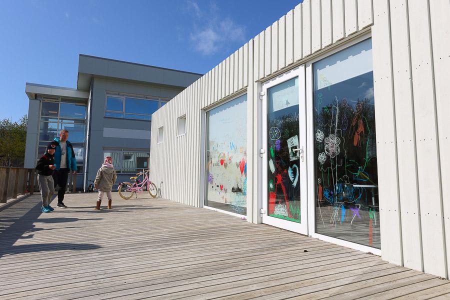 The Neðstaland after-school program building seen from outside. Parent with children. 
