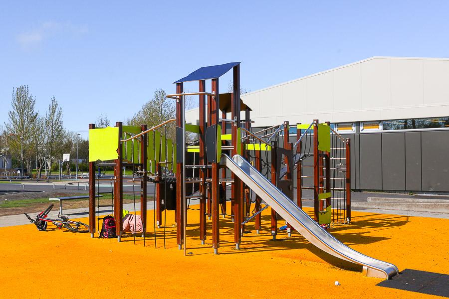 Play structure with slide and climbing frame on orange flooring.