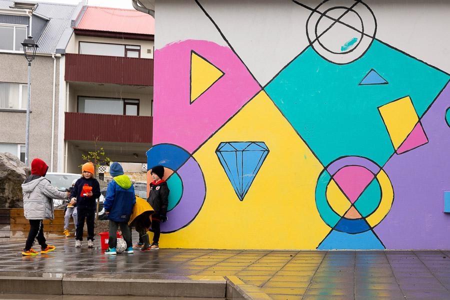 Large illustrated wall outdoors with children standing in a group in front.