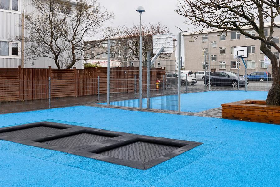 Outdoor area at Vesturbæjarskóli and Skýjaborg after-school program with blue surface and trampoline.