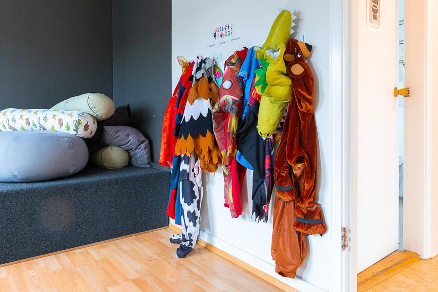 Costumes for children to play dress-up in, hanging on the wall. 