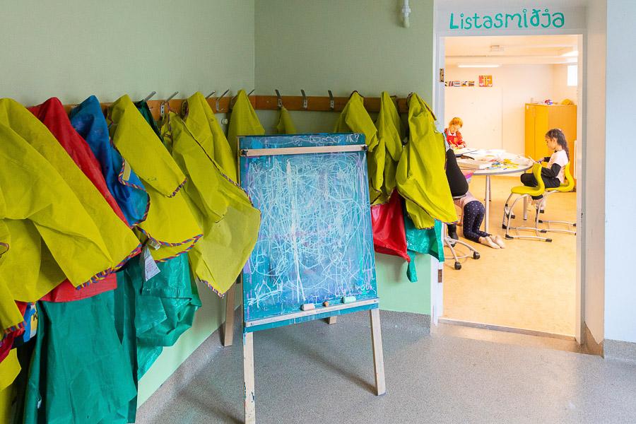 Doorway with the heading "Art workshop," smocks and vests to protect clothing from paint splatters hanging on the wall. 