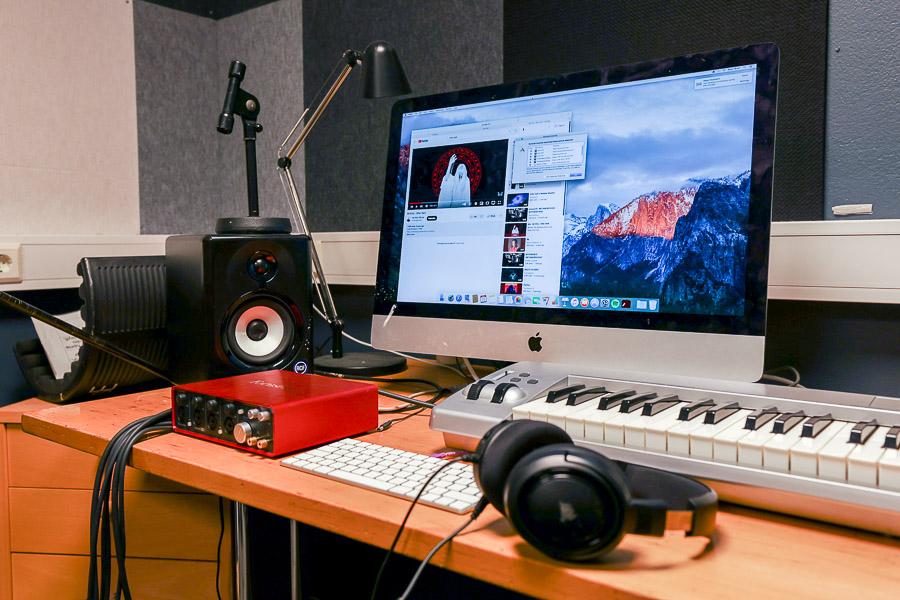 Table with computer monitor, keyboard, speakers and other equipment.