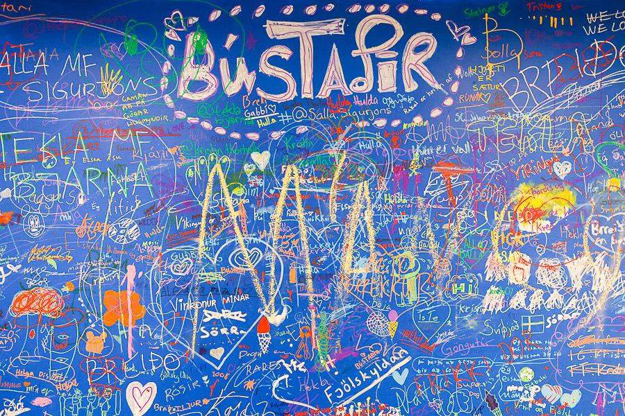 Large blue board with various artwork and the heading Bústaðir