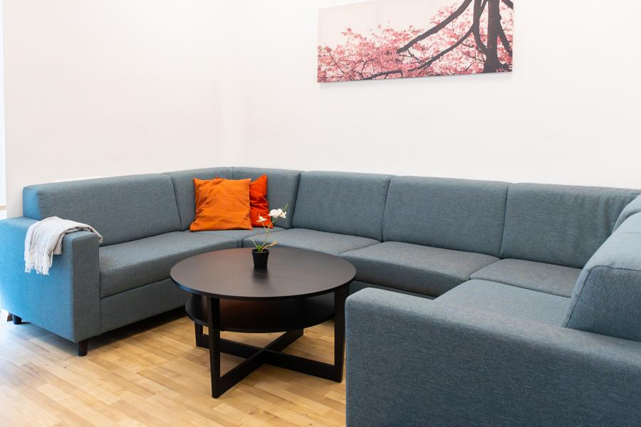 Gray corner couch and small table. Picture on the wall above the couch. 