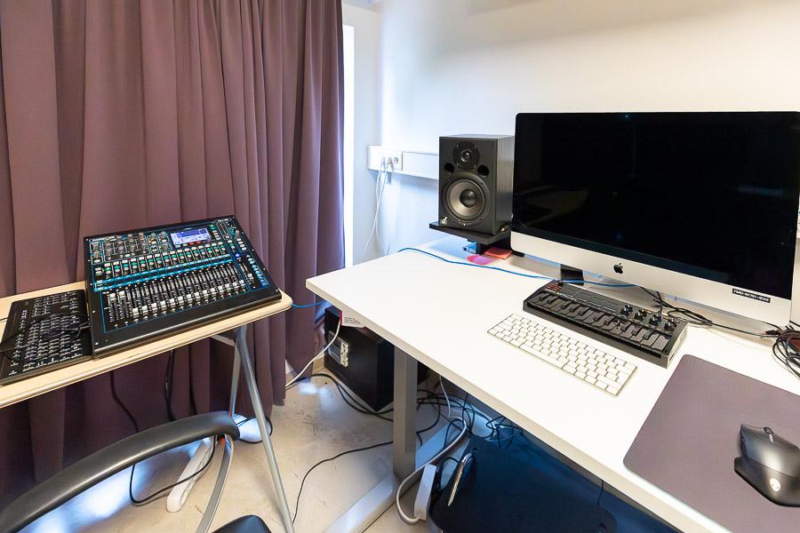 Table with a computer screen, an audio mixer, speakers, and more.