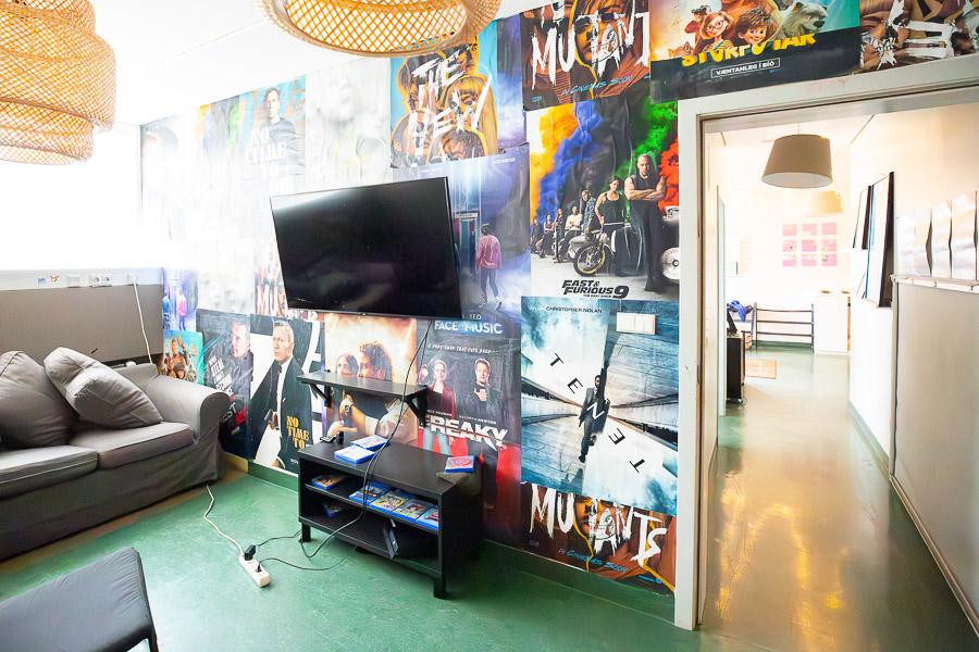 Wall covered with movie posters. Screen on the wall and couch to the side. 
