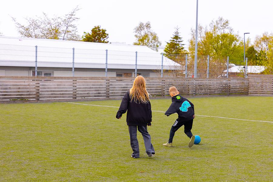 Children playing soccer on an outdoor grass field.