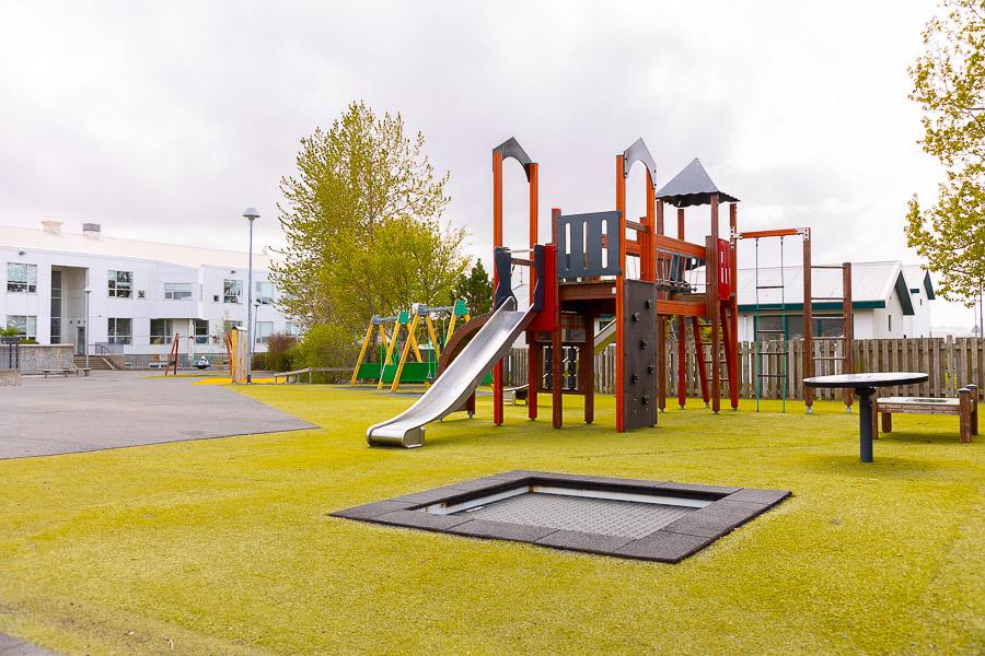 A playground with a castle, a slide, and a trampoline.