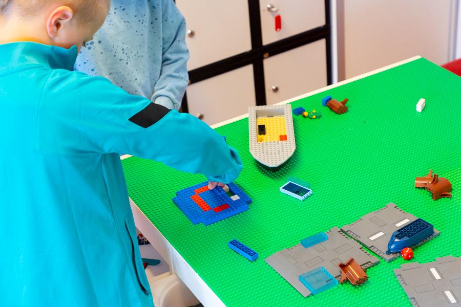 A child building with Lego blocks on a table.
