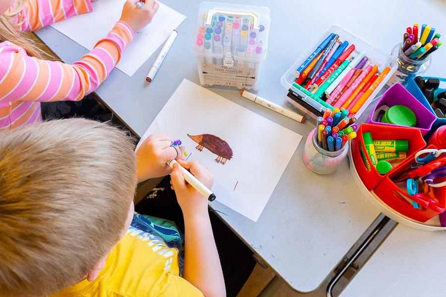 Children sit at a table drawing and coloring.