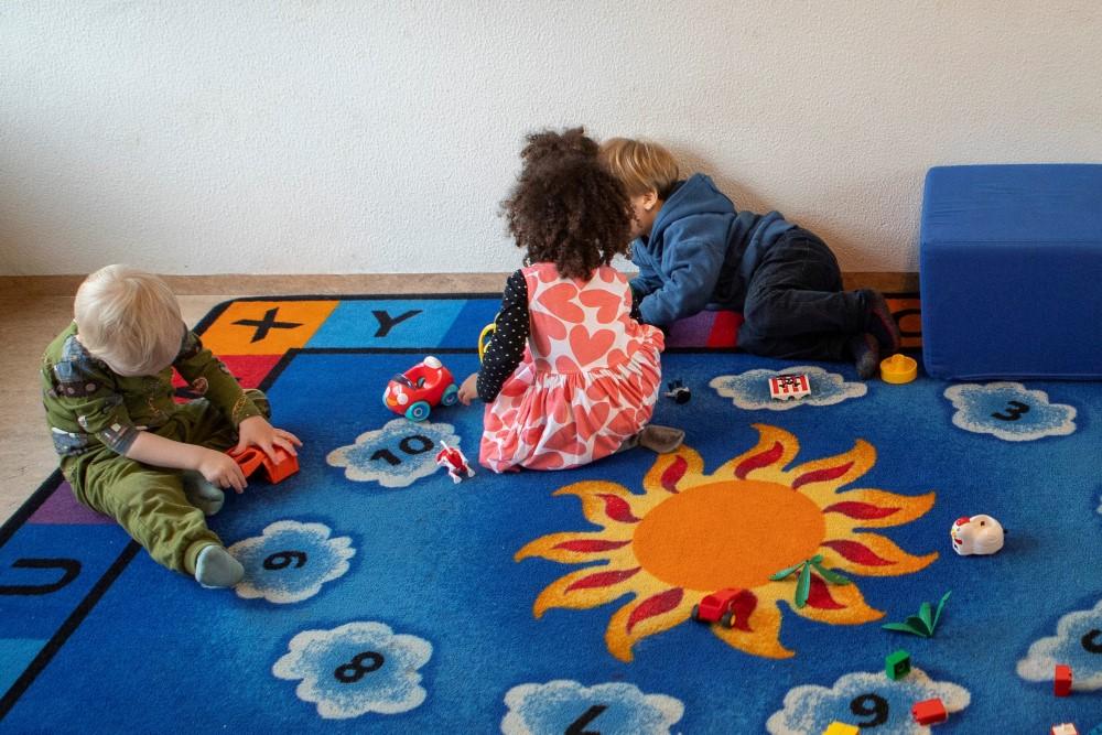 Children playing on a blue carpet with sun pattern.
