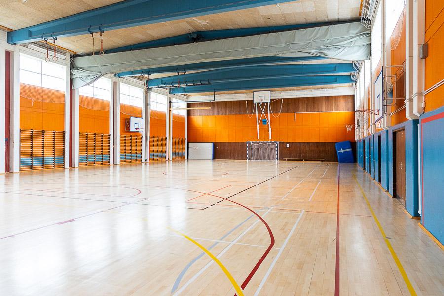 A gymnasium equipped with a soccer goal and basketball hoops. 