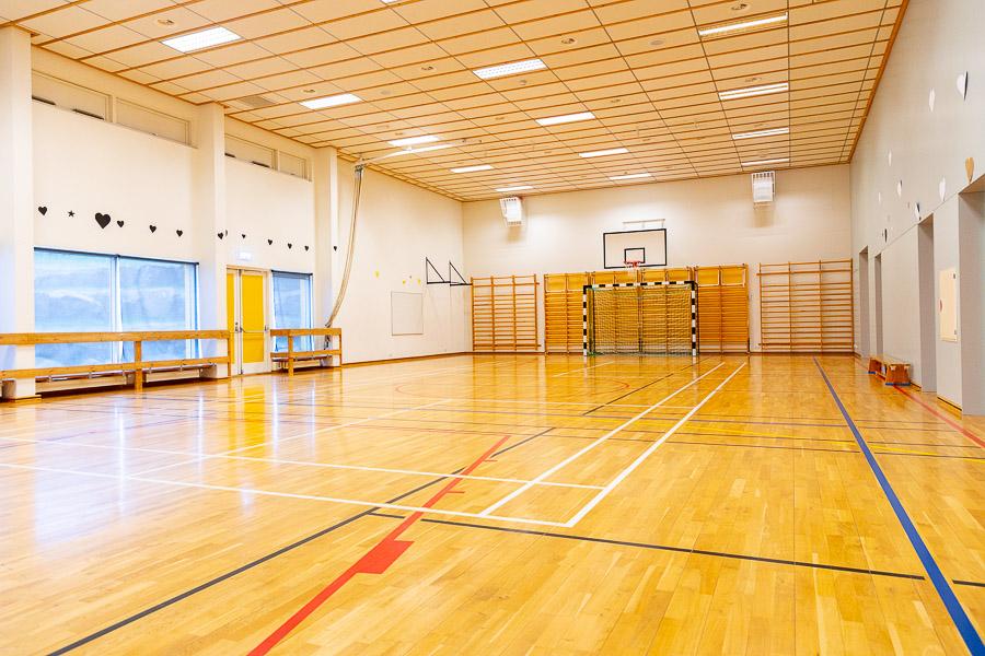 A gymnasium equipped with a soccer goal and basketball hoops. 