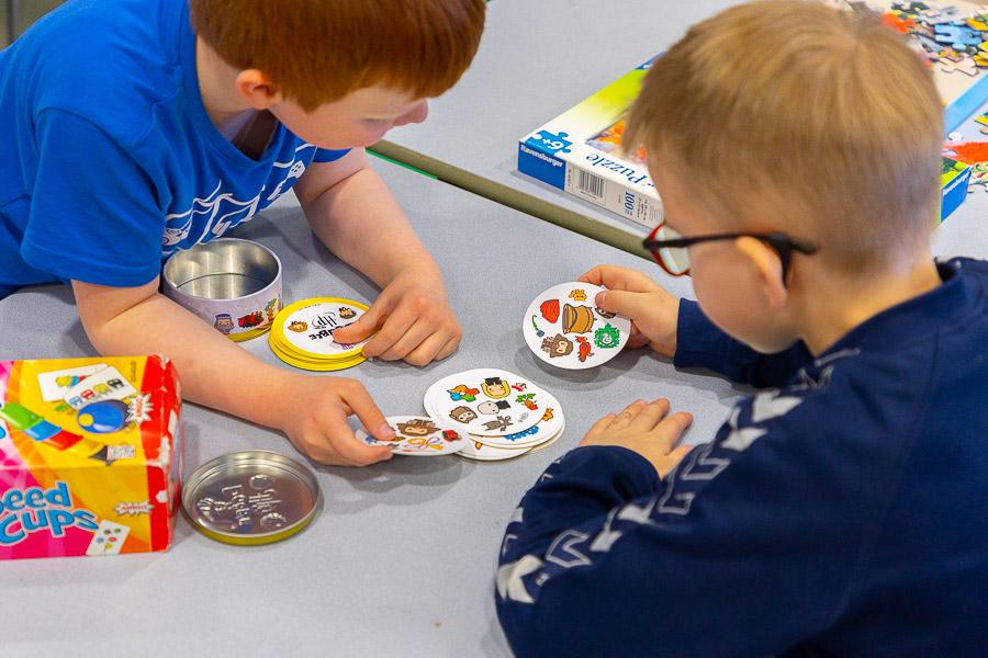 Children sit at a table playing with picture cards. 