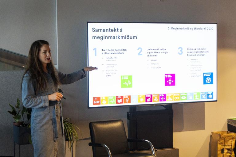 Harpa Þorsteinsdóttir, verkefnastjóri lýðheilsumála á skrifstofu borgarstjóra og borgarritara heldur framsögu um Heilsu og líðan hinsegin fólks í Pollinum í Ráðhúsinu. Stendur við skjá og bendir á gögn